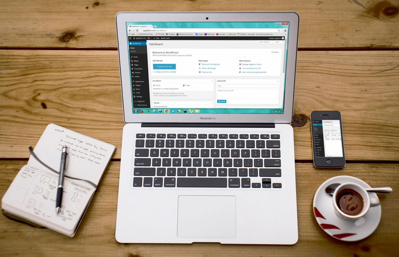 Une scène de bureau à domicile chaleureuse avec un ordinateur portable, un carnet, un smartphone et un café, idéale pour travailler efficacement.